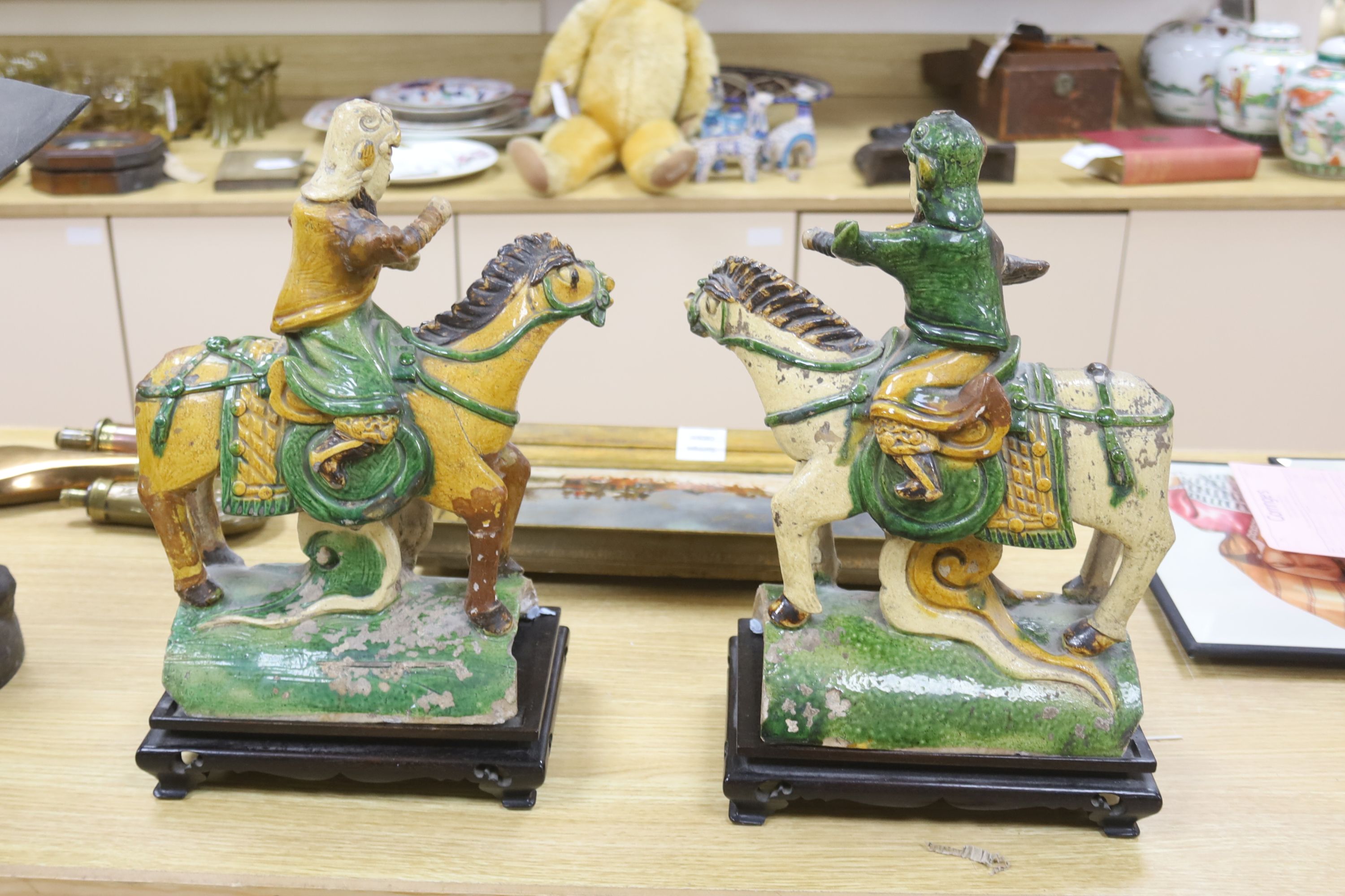 A pair of Chinese Ming sancai ‘horse and rider’ ridge tiles, height 38cm on wooden stand